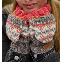A close-up of a person wearing a chunky knit winter accessory with a bright pink ruffled cuff and gray, white, pink, and teal patterned sections.