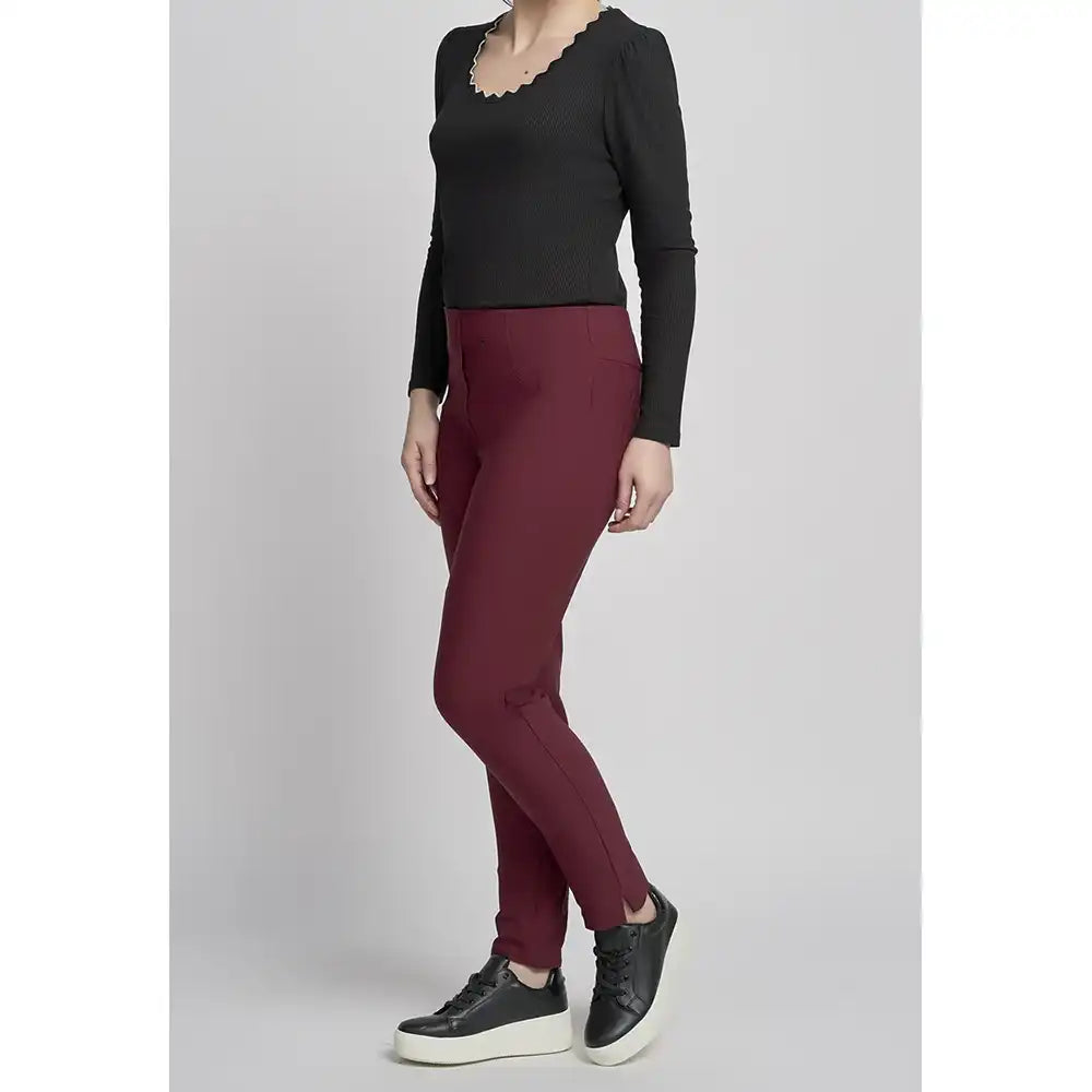 Person wearing a black top and maroon pants on a light gray background