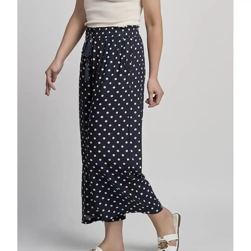 Navy blue skirt with white polka dots worn by a person on a gray background