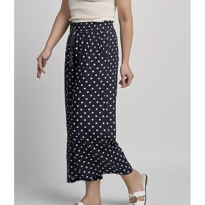 Navy blue skirt with white polka dots worn by a person on a gray background