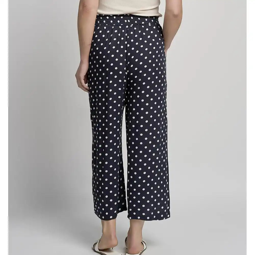 Person wearing navy blue pants with white polka dots on a plain background