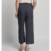 Person wearing navy blue pants with white polka dots on a plain background