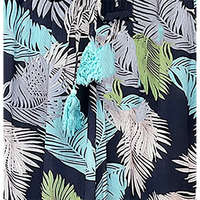 Hawaiian shirt with tropical leaf pattern and tassels on a dark background