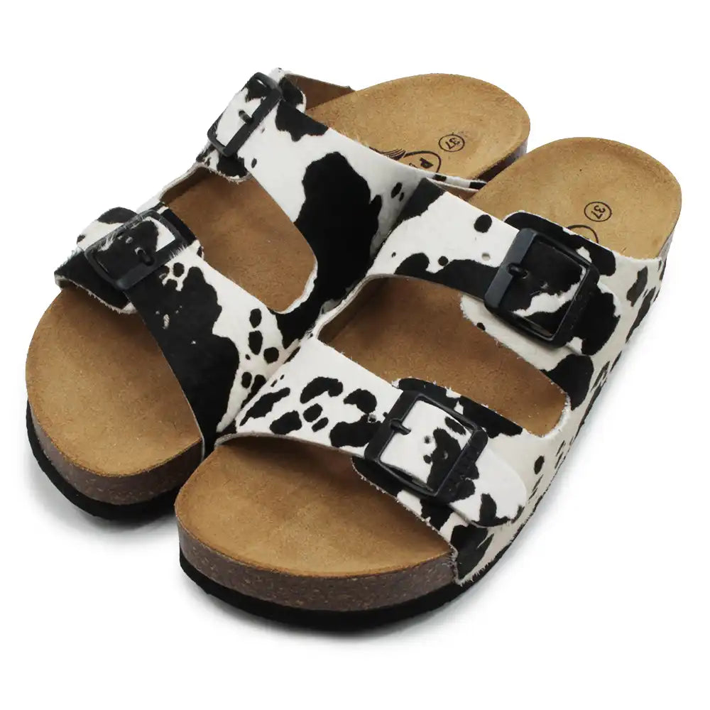Pair of sandals with cow print pattern on a white background