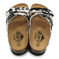 Pair of sandals with black and white cow pattern on a white background