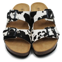 Pair of sandals with cow print pattern on a white background