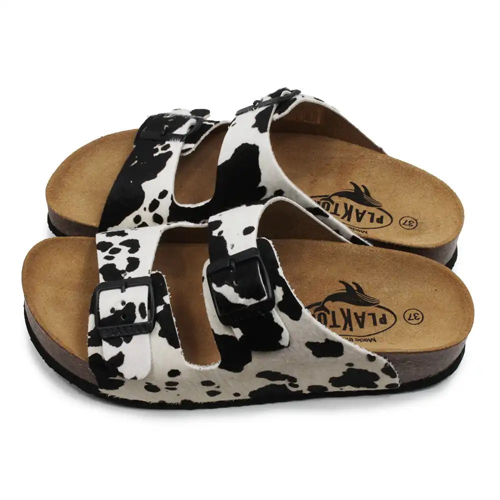 Pair of sandals with cow print straps on a white background