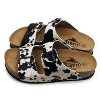Pair of sandals with cow print straps on a white background