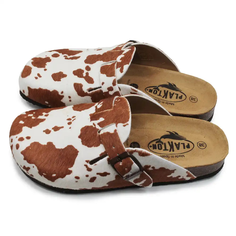 Pair of cow print sandals with wooden soles on a white background