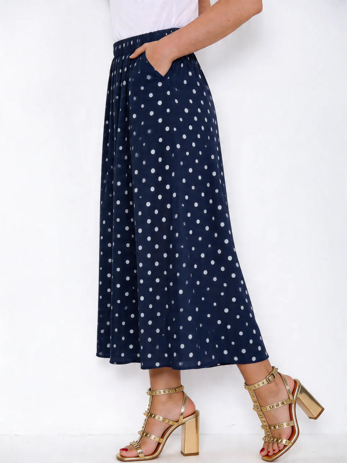 Navy blue polka dot skirt worn by a person on a white background