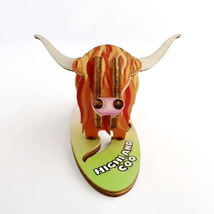 A 3D wooden model of a Highland cow on a light green base labeled 'HIGHLAND COW', photographed against a plain white background.