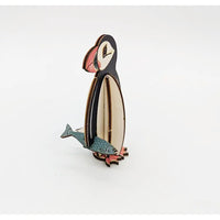 Wooden penguin ornament holding a fish on a white background