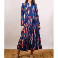 Woman wearing a colorful patterned dress against a plain background