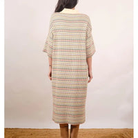 Person wearing a long, patterned dress against a plain background