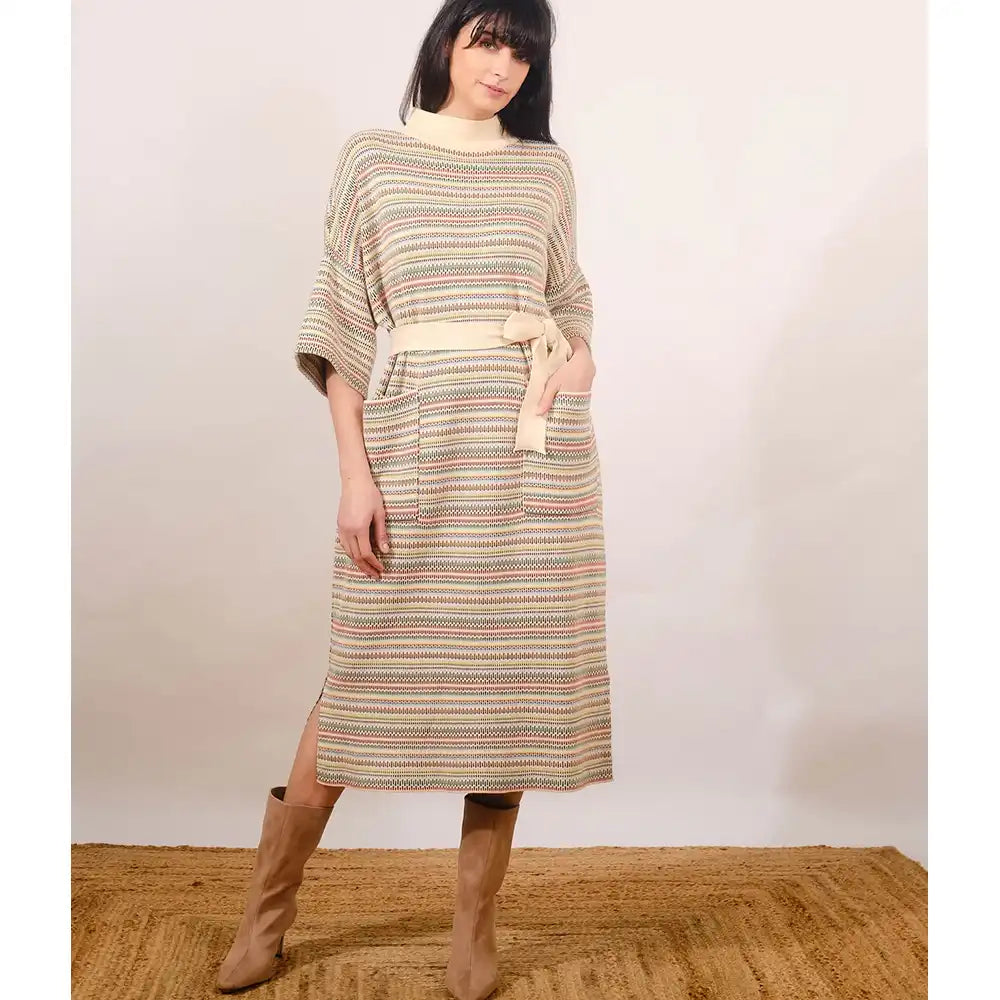 Woman wearing a patterned dress with a belt against a plain background