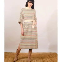 Woman wearing a patterned dress with a belt against a plain background