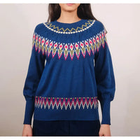 Blue sweater with colorful pattern worn by a person on a plain background