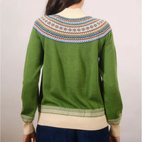 Green sweater with patterned shoulders worn by a person on a plain background