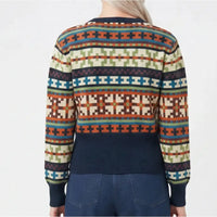 A person shown from the back wearing a long-sleeve knit sweater with a multicolor geometric Fair Isle pattern and a solid navy ribbed hem, cuffs, and collar, paired with blue jeans against a plain white background.
