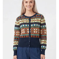 A woman wearing a long-sleeve button-front cardigan with a multicolor geometric pattern and solid navy ribbed trim, paired with navy pants, against a light gray studio background.