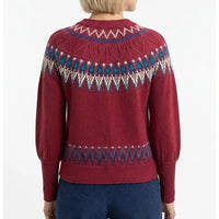 A woman shown from the back wearing a burgundy Fair Isle knit sweater with blue and cream geometric patterns across the shoulders and upper back, paired with dark blue corduroy pants against a plain white background.