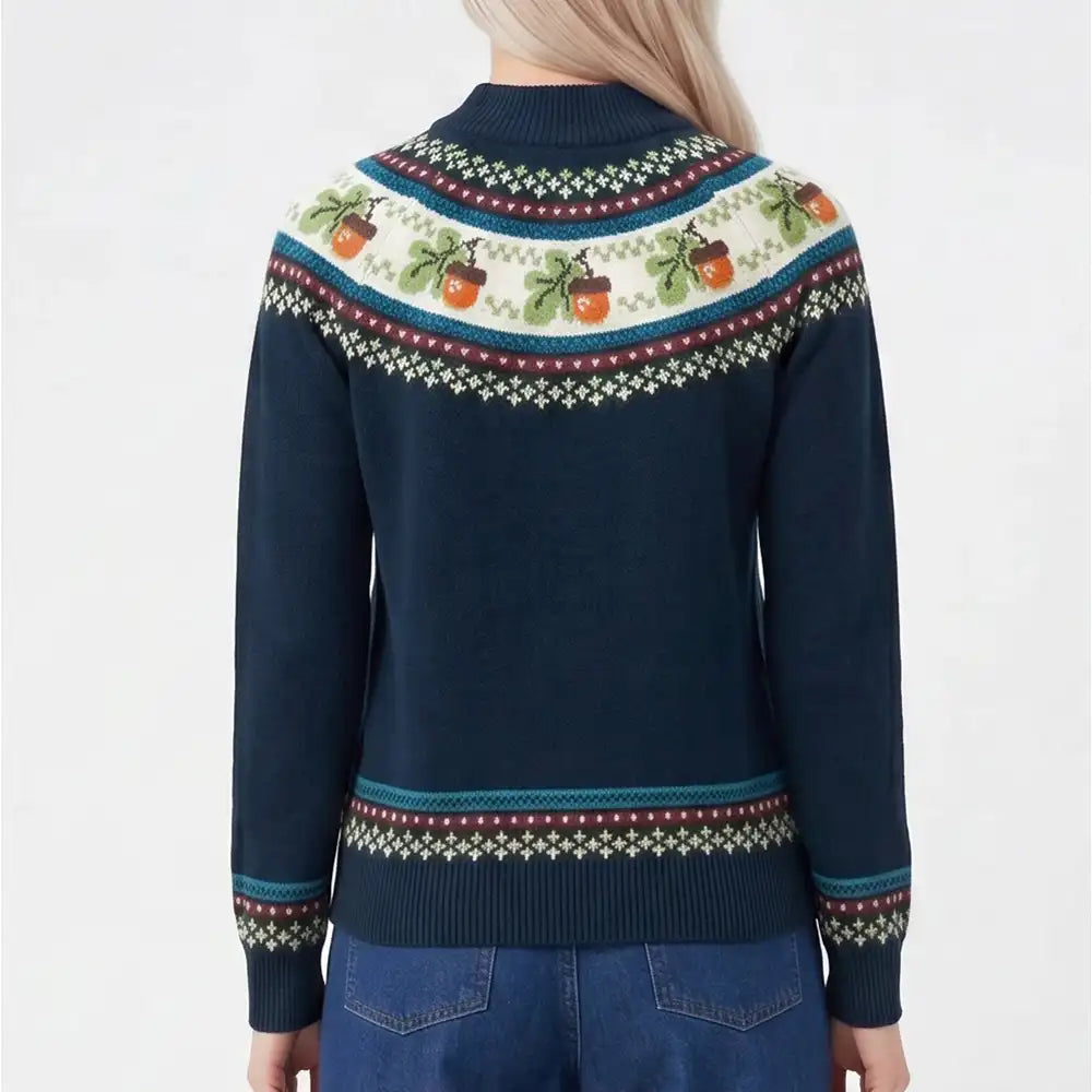 A woman viewed from the back wearing a navy blue knit sweater with a colorful Fair Isle pattern across the shoulders and cuffs, paired with blue jeans against a plain white background.