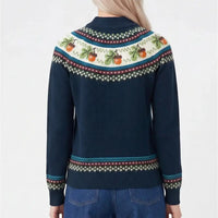 A woman viewed from the back wearing a navy blue knit sweater with a colorful Fair Isle pattern across the shoulders and cuffs, paired with blue jeans against a plain white background.