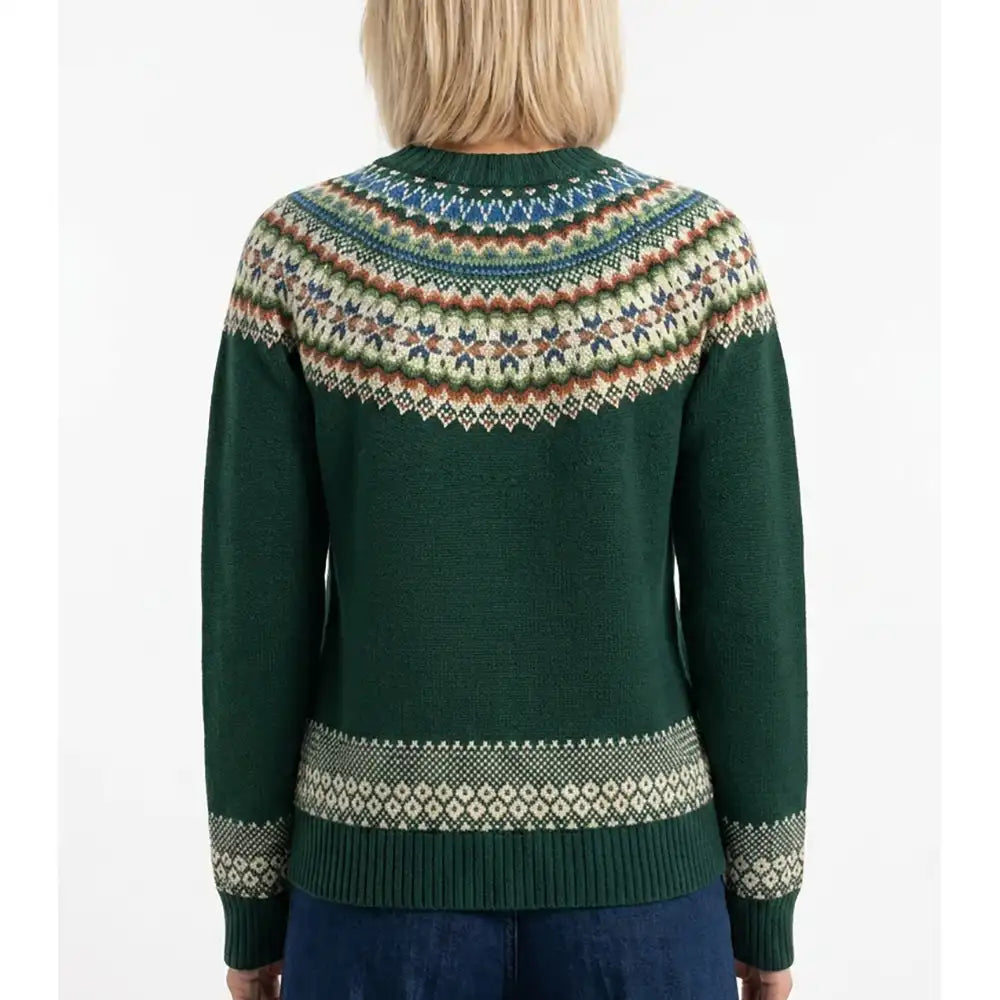 A woman viewed from the back wearing a dark green knit sweater with a multicolor Fair Isle yoke and sleeve cuffs, paired with blue jeans against a plain white background.