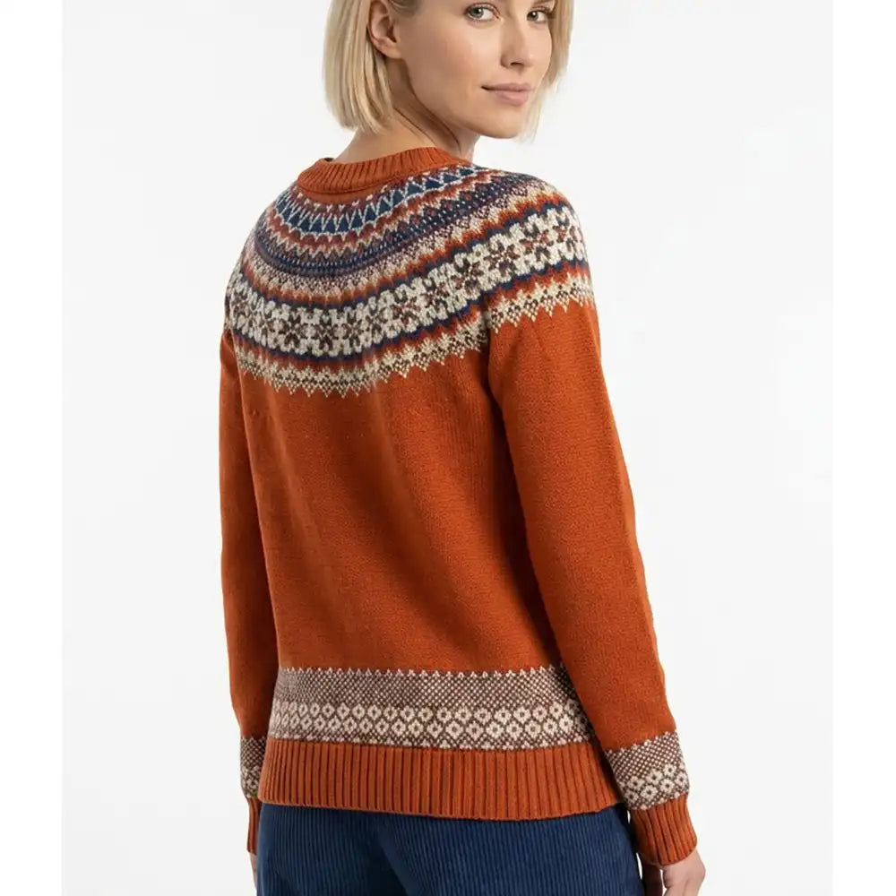 A woman wearing a rust-orange Fair Isle knit sweater with a colorful patterned yoke and cuffs, shown from a three-quarters back view against a white studio background.