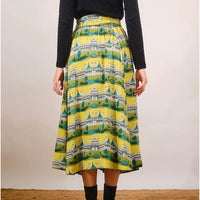 Person wearing a yellow patterned skirt with a plain background