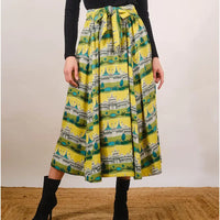 Person wearing a yellow skirt with architectural print on a plain background