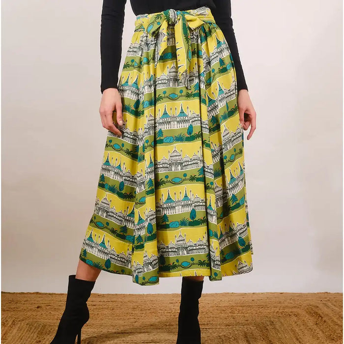 Person wearing a yellow skirt with architectural print on a plain background