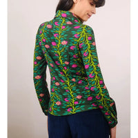 Woman wearing a green floral patterned shirt against a plain background