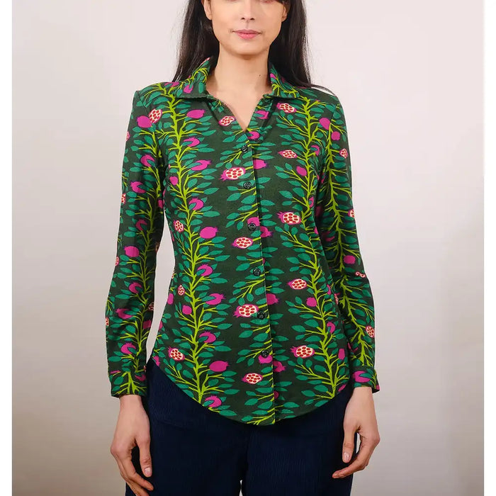 Woman wearing a green floral patterned shirt against a plain background