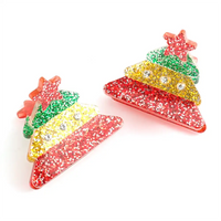 Picture of two mini Christmas Tree hair claw clips  with a glitter finish and stars on the top. 