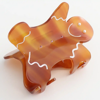 Picture of a smiling gingerbread man  hair claw clip  in brown and white. star.