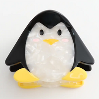 Picture of a penguin hair claw clip  in black and white with yellow feet. 
