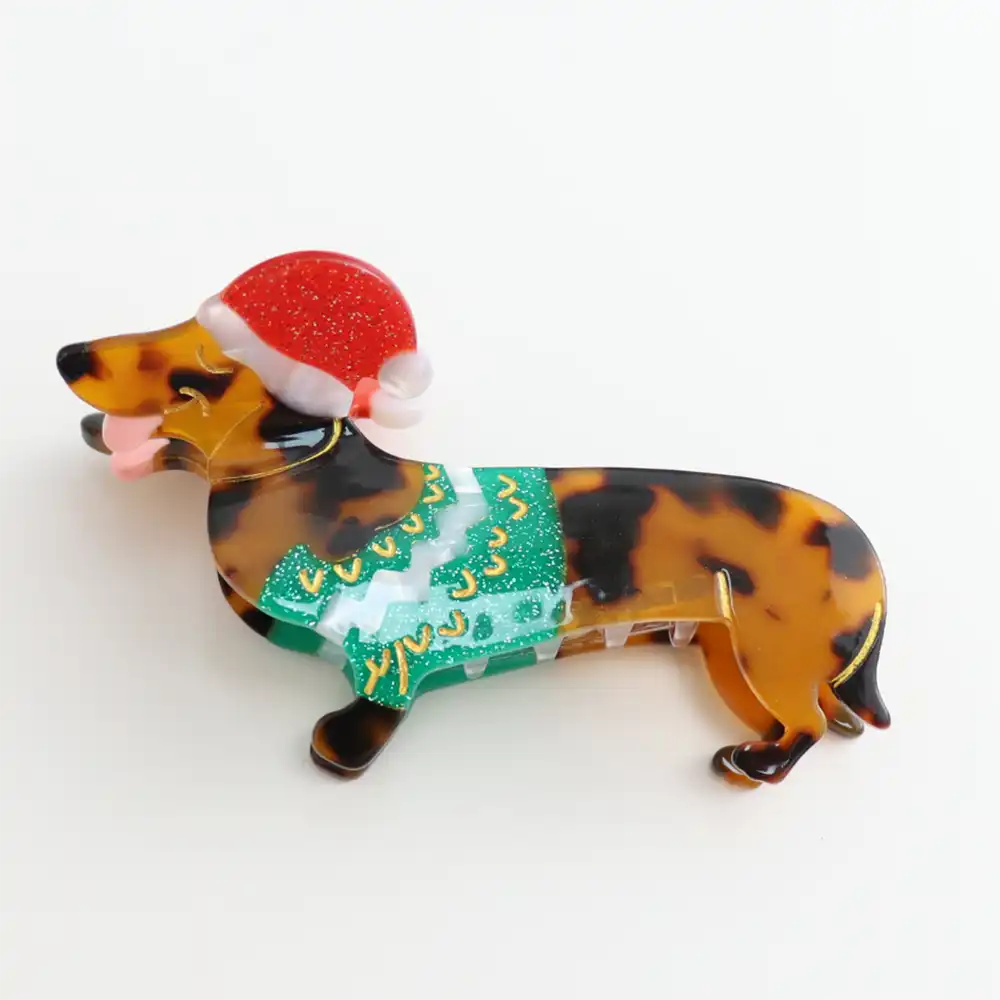 Picture of a dappled brown Christmas dachshund hair claw clip  who wears a Christms hat and a green waistcoat.