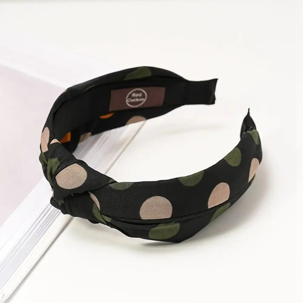 Navy based alice band with a grey and deep green spotty pattern. 