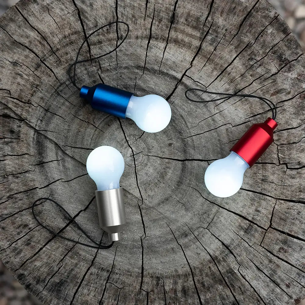 Three LED light bulbs in different colours on a wooden surface