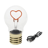 Light bulb with heart-shaped filament and USB cable on a white background