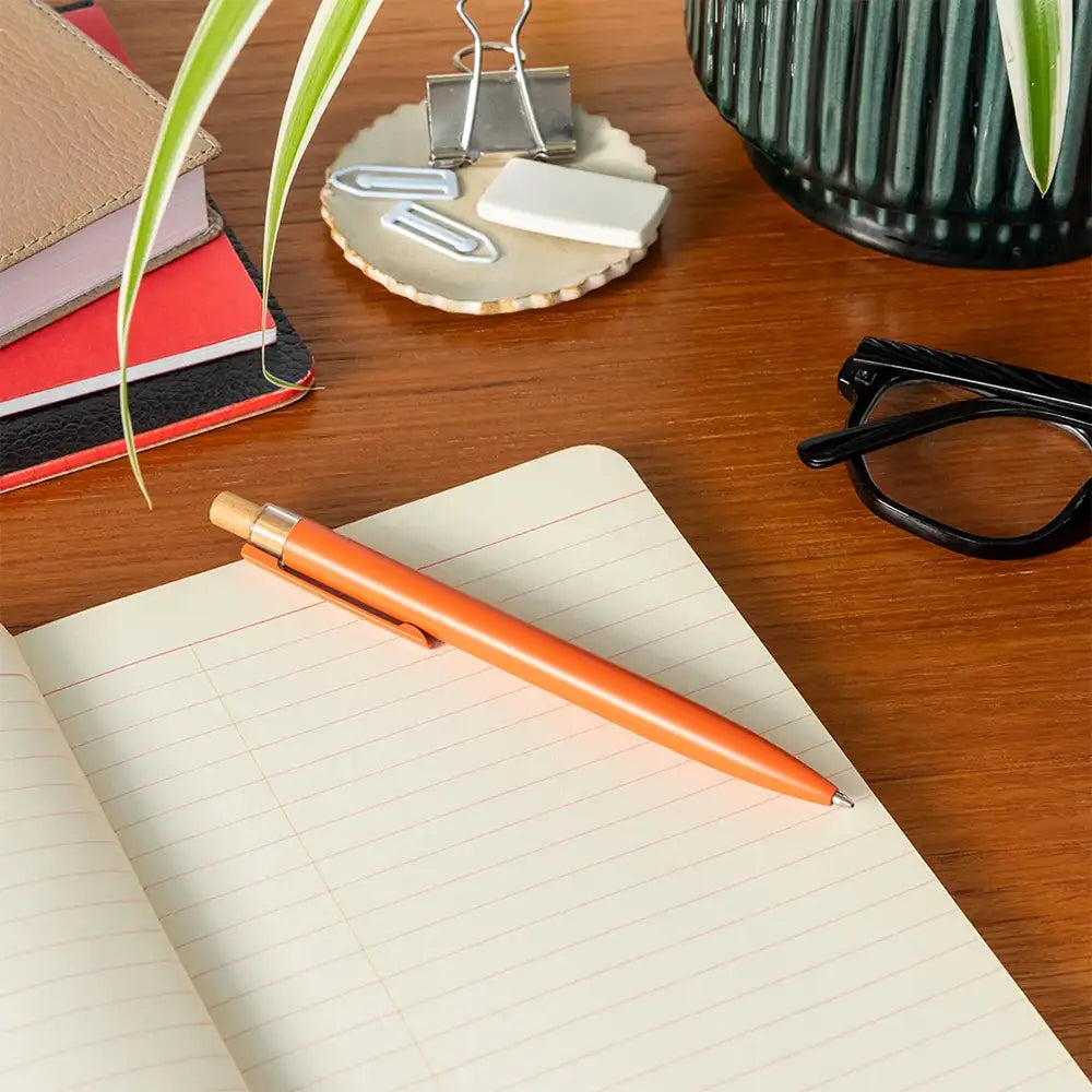 Orange pen on a lined sheet of paper. 