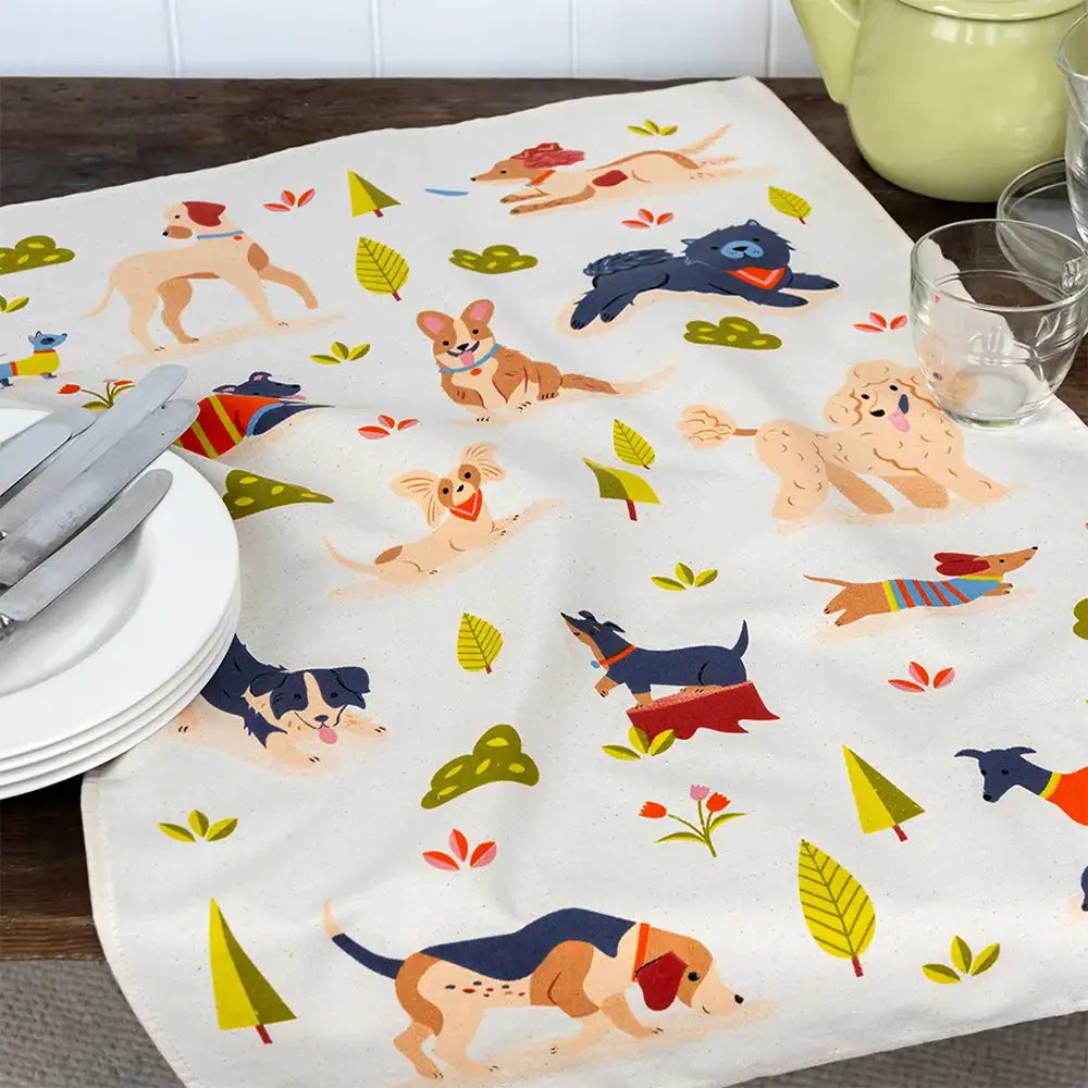 Tablecloth with dog pattern on a table with plates and cutlery.