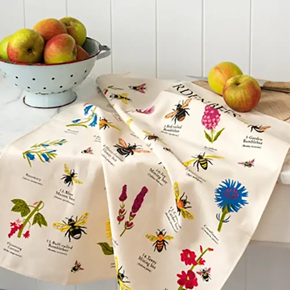 Two decorative kitchen towels with bee and flower patterns on a kitchen counter.