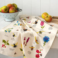 Two decorative kitchen towels with bee and flower patterns on a kitchen counter.