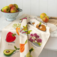 Two kitchen towels with vegetable and fruit designs on a marble countertop.