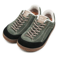 A pair of low-top slip-on shoes with an olive green suede upper, black toe caps, beige braided laces, and a white sherpa lining, shown on a white background.