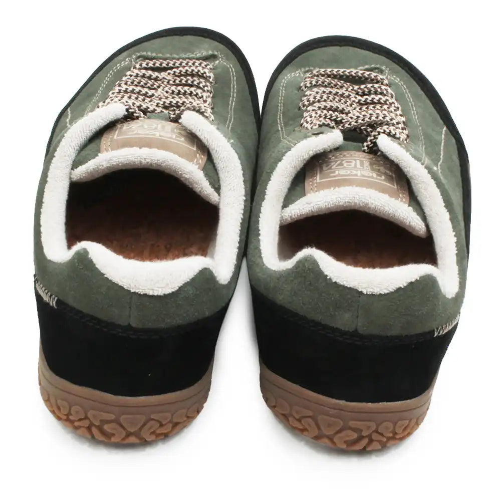 A pair of Vans slip-on sneakers in olive green suede with white sherpa lining, brown laces, and black soles, shown from a top-down view on a white background.