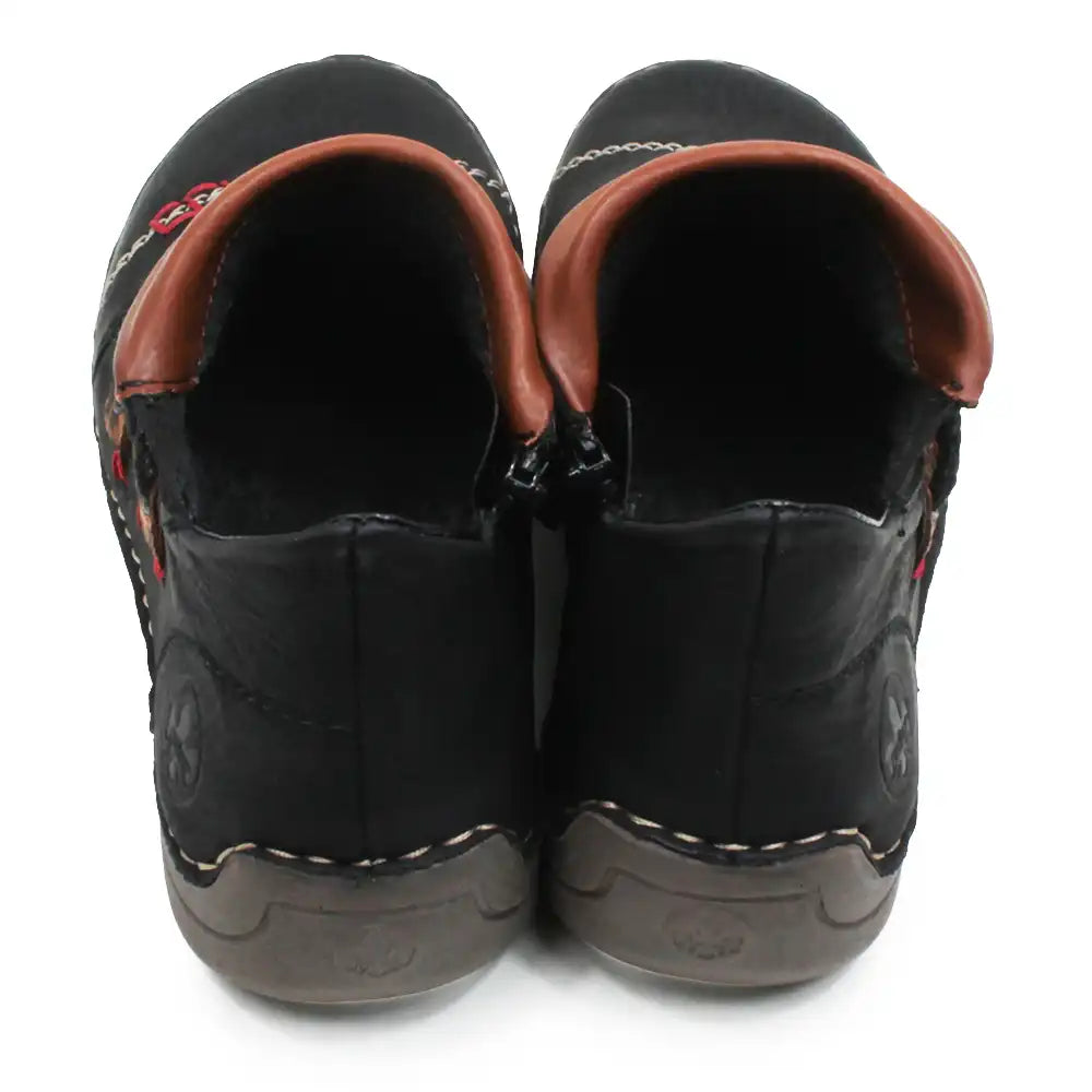 A pair of black faux leather slip-on shoes with brown faux leather trim around the collar and a dark gray sole, shown from a back-facing angle on a white background.