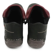 A pair of green faux leather slip-on shoes with burgundy inner lining and white contrast stitching, shown from the back on a white background.